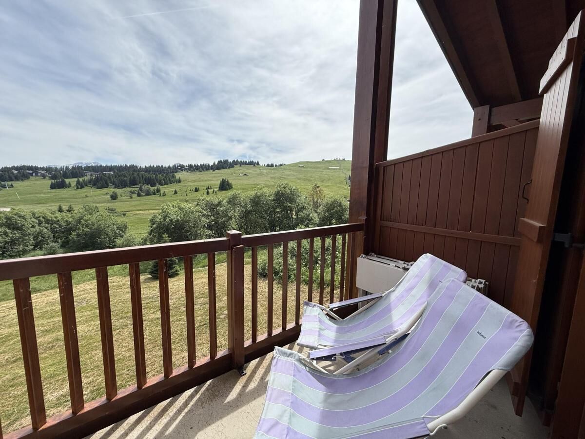 Un balcon donnant sur un paysage verdoyant et sur une montagne lointaine.