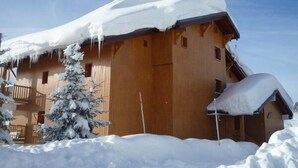 Een houten hut met een sneeuwbedekte dak en een klein terras.