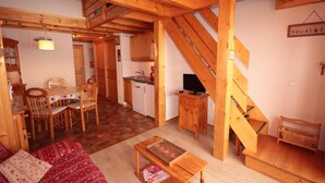 Een gezellig houten interieur met een eetgedeelte, keuken en een trap.