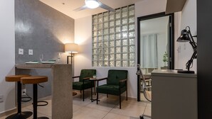 A modern kitchen with a bar area, green upholstered chairs, a large window with frosted glass, and a ceiling fan. - In Front of the Underground and 8 Minutes From the Beach Sf228 (Rio de Janeiro)
