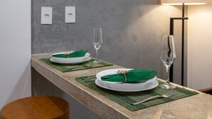 A neatly set dining table with green placemats, white plates, and clear glassware on a granite countertop. - In Front of the Underground and 8 Minutes From the Beach Sf228 (Rio de Janeiro)