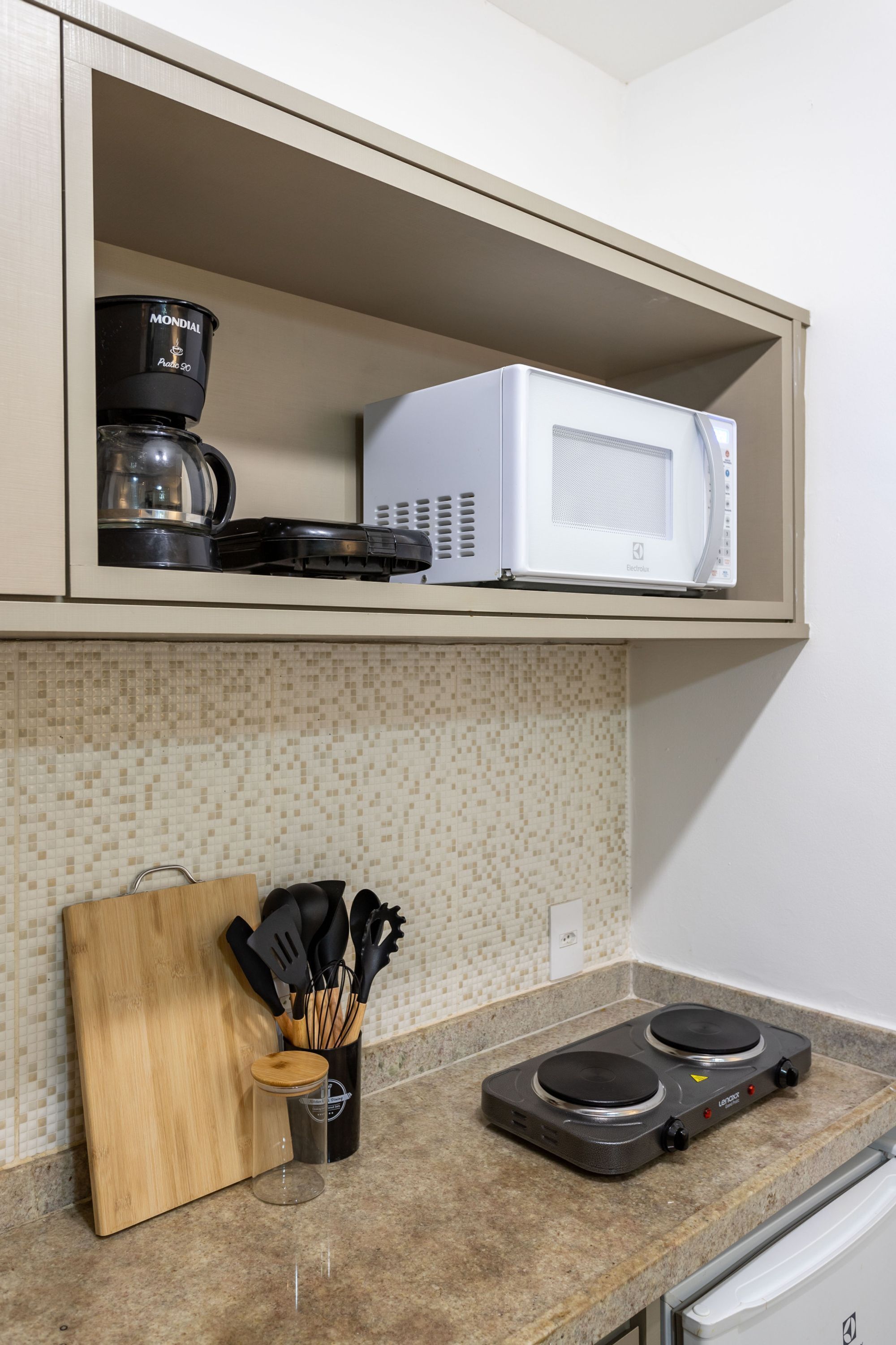 A kitchen with a microwave, coffee maker, and induction cooktop on the countertop.