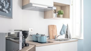 Una cocina moderna con horno empotrado, cafetera y tabla de cortar de madera.