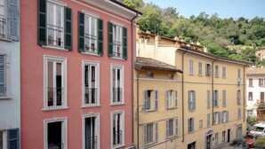 Una hilera de edificios de varios pisos con balcones, una calle al frente y coches estacionados.