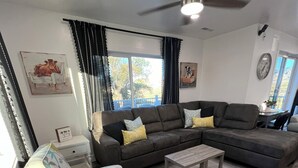 A living room with a sectional sofa, a small white table, and a ceiling fan. - Escape to Luxurious Lynndyl Resort—Nature, Comfort & Serenity Await (Lynndyl)