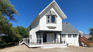 A white two-story house with a gabled roof, a front porch, and a staircase leading to the entrance. - Escape to Luxurious Lynndyl Resort—Nature, Comfort & Serenity Await (Lynndyl)