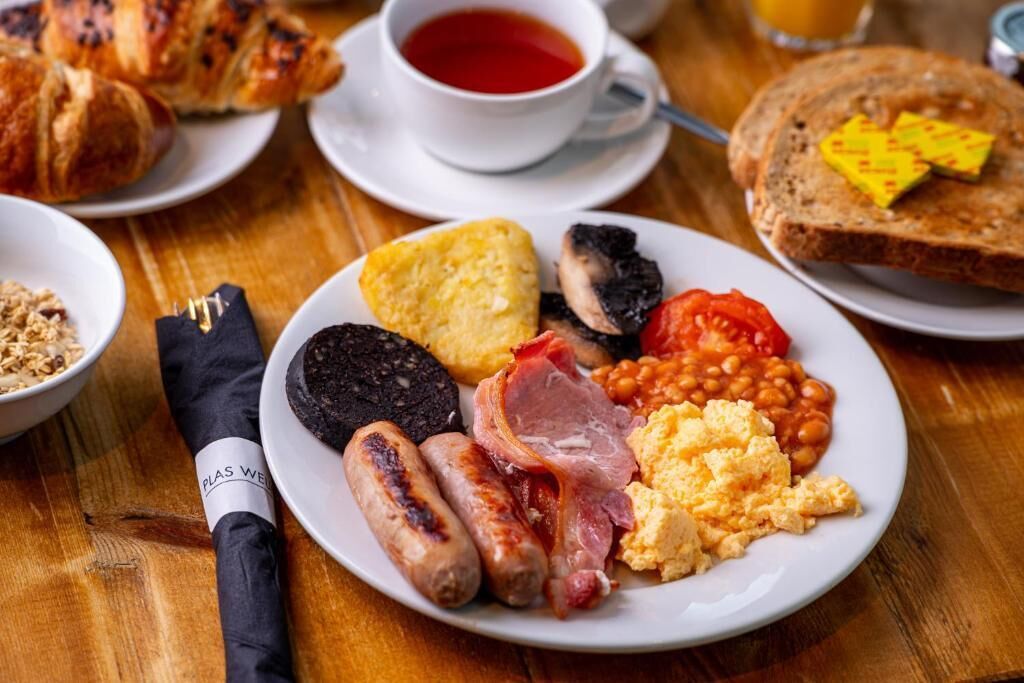A breakfast plate with sausages, eggs, beans, tomatoes, and toast.