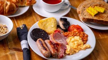 A breakfast plate with sausages, eggs, beans, tomatoes, and toast.