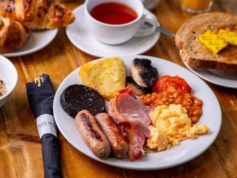 A breakfast plate with sausages, eggs, beans, tomatoes, and toast.