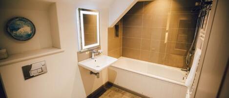 Une salle de bain avec un lavabo blanc, un miroir et une baignoire.