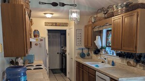 A kitchen with wooden cabinets, a water dispenser, a sink, and a dining area with chairs.