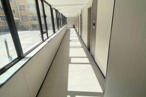 A corridor with large windows, a fire extinguisher, and a door on the right. - Altay Fenglinwan Boutique Hotel (Altay City)