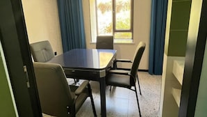 A conference room with a table and four chairs, a window with curtains, and an air conditioning unit on the wall. - Altay Fenglinwan Boutique Hotel (Altay City)