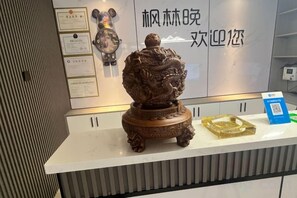Un mostrador de recepción con una estatua de bronce decorativa, diplomas enmarcados y un código QR en la encimera.