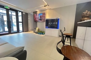 Un área de recepción con televisión, asientos y una pared decorativa.