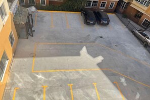 A parking lot with marked spaces, a building entrance, and parked cars. - Altay Fenglinwan Boutique Hotel (Altay City)