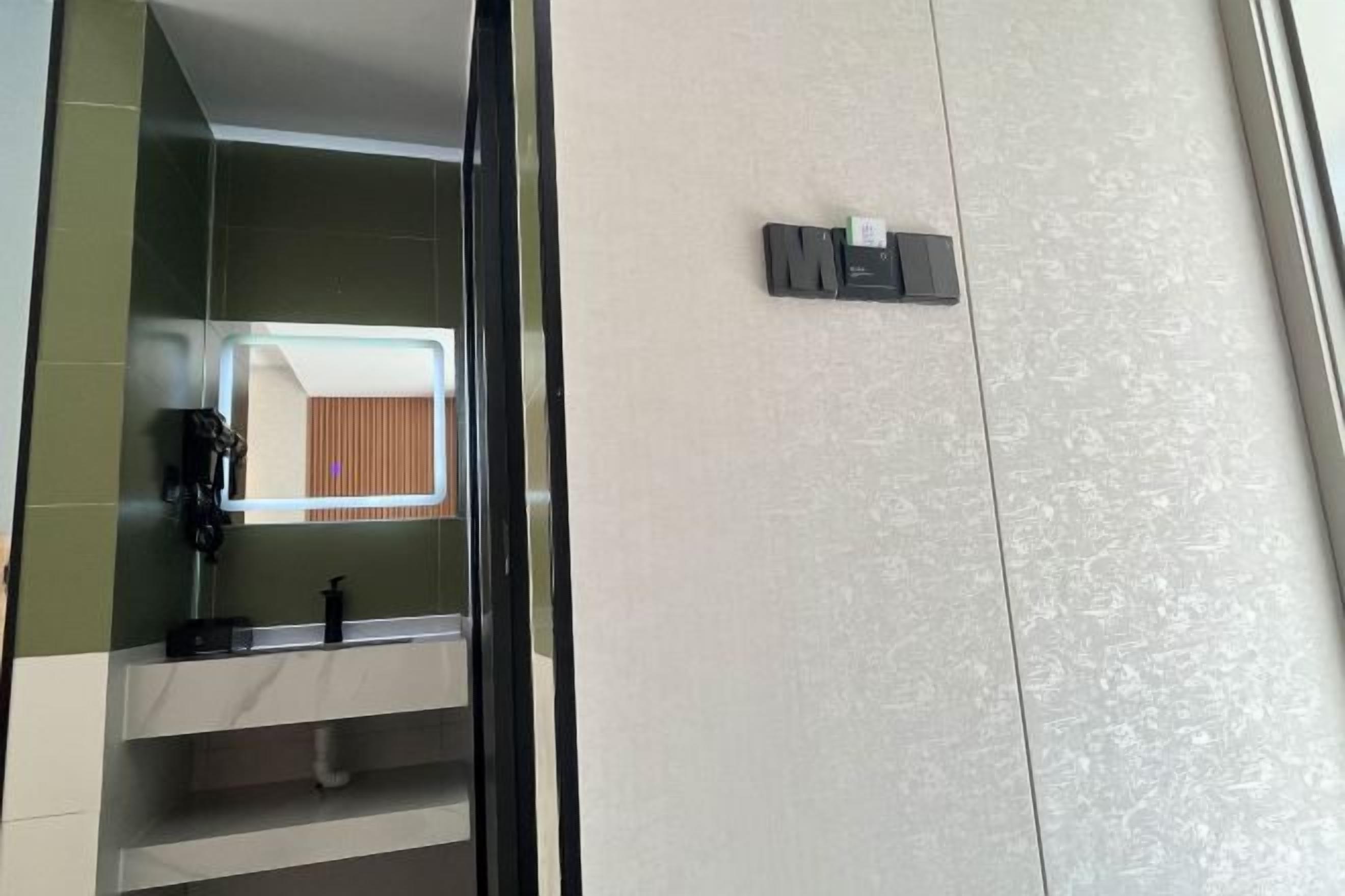 Un baño con espejo, lavamanos y toallero.