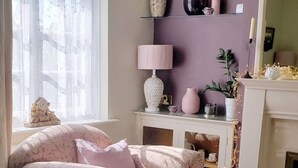 A cozy room with a patterned armchair, a small table with a lamp, and a fireplace. - Lavender Cottage, a pretty period cottage in Louth (Louth)
