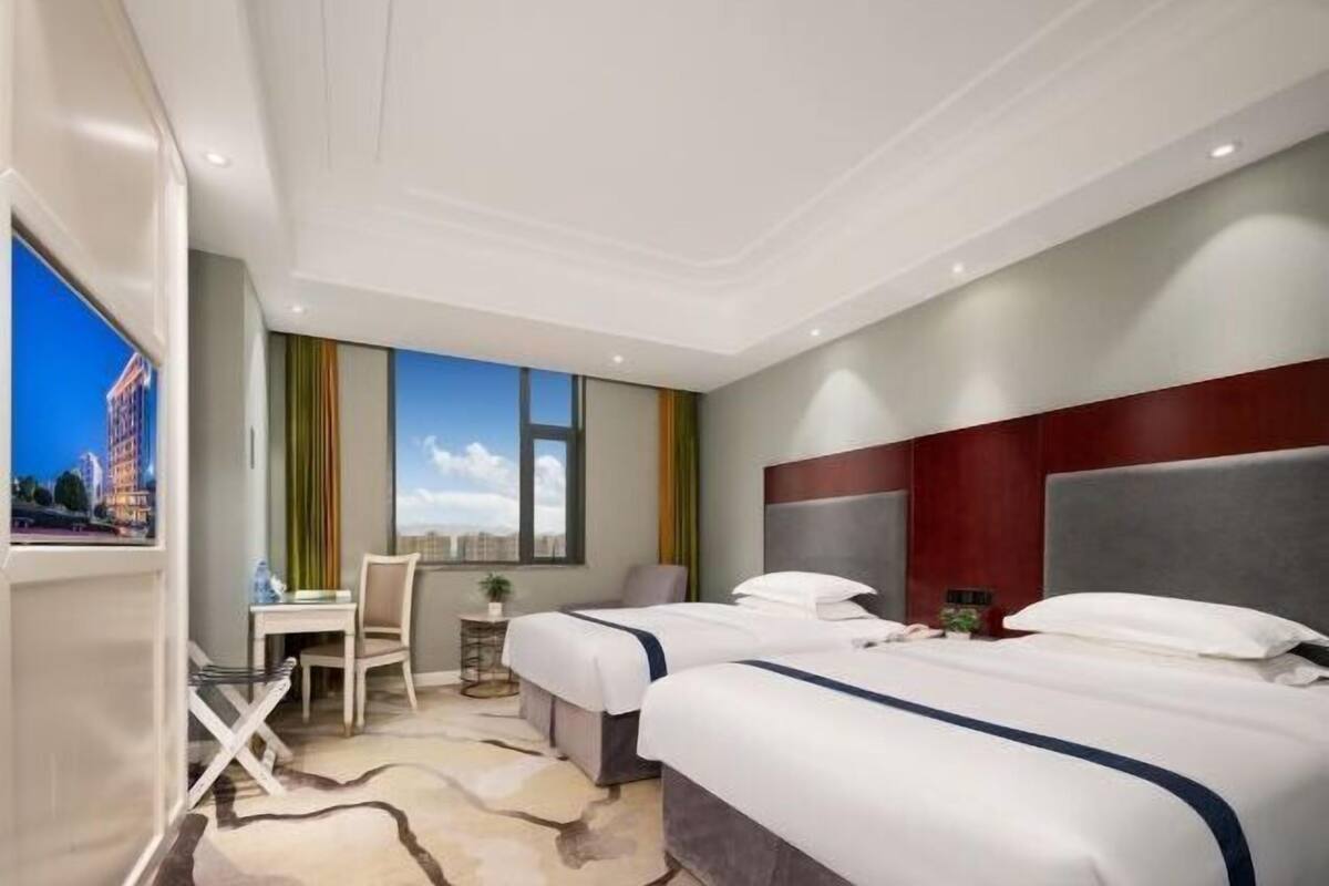 Ein Hotelzimmer mit zwei Betten, einem Schreibtisch und einem Stuhl.