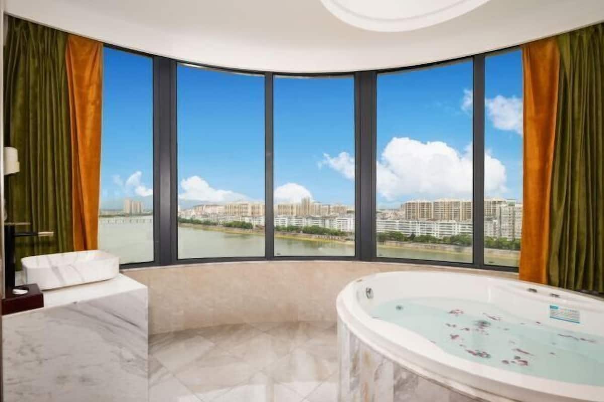 Ein modernes Badezimmer mit einer großen Badewanne, einem мраморм Waschbecken und Blick auf die Stadt durch große Fenster.