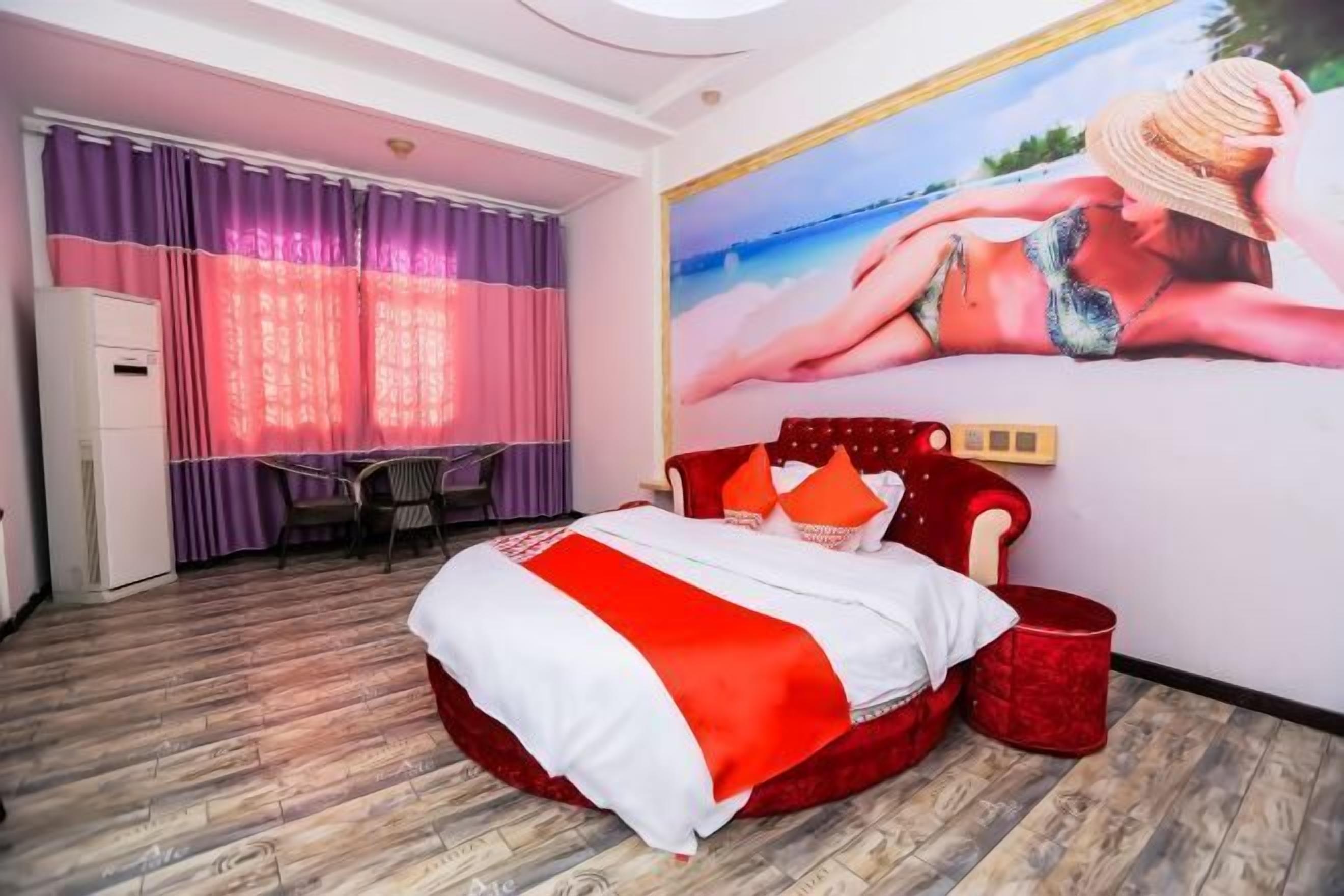 A bedroom with a bed, a desk, a chair, and a large beach-themed mural on the wall.