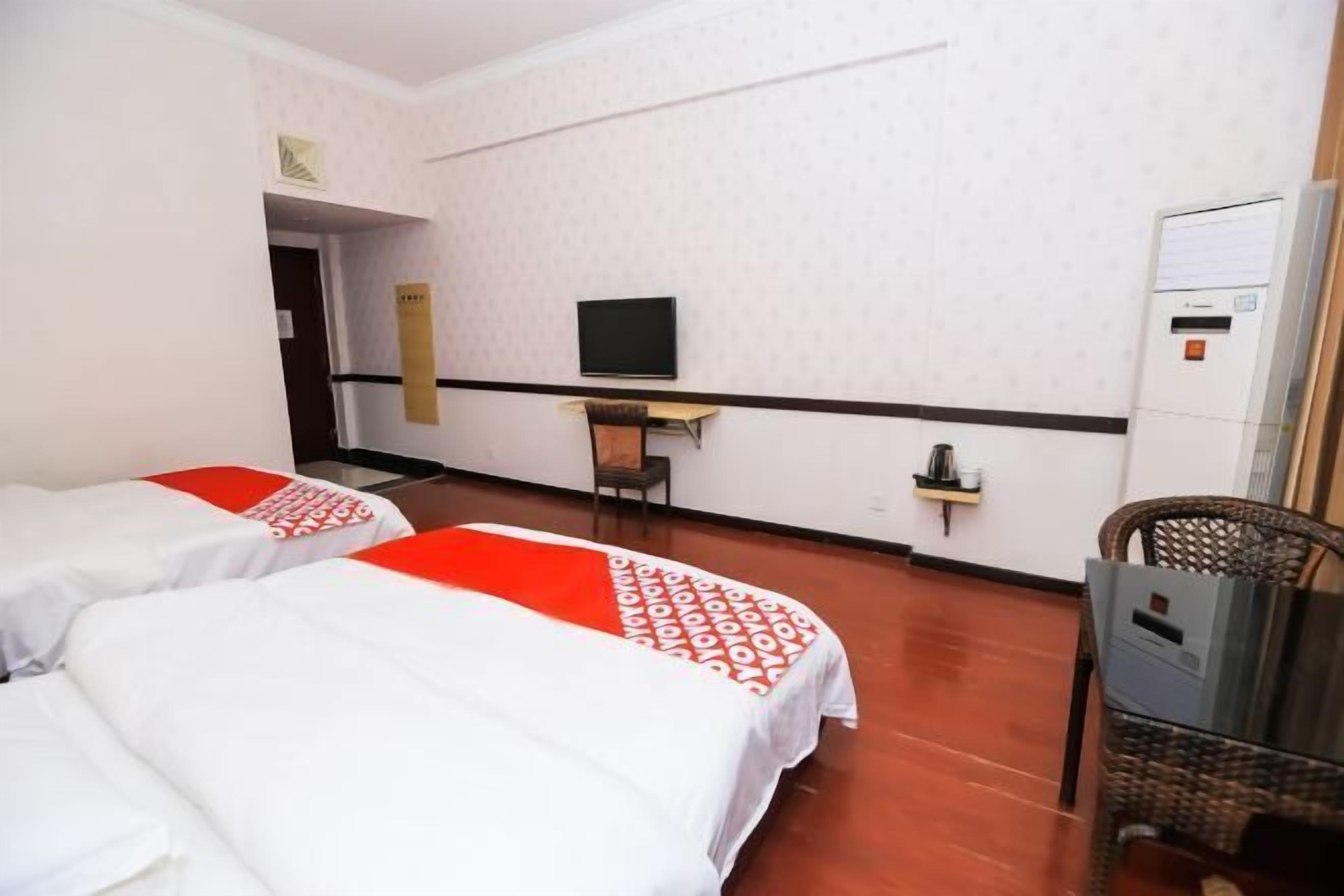 Ein Hotelzimmer mit zwei Betten, einem Fernseher, einem Schreibtisch und einem Sessel.