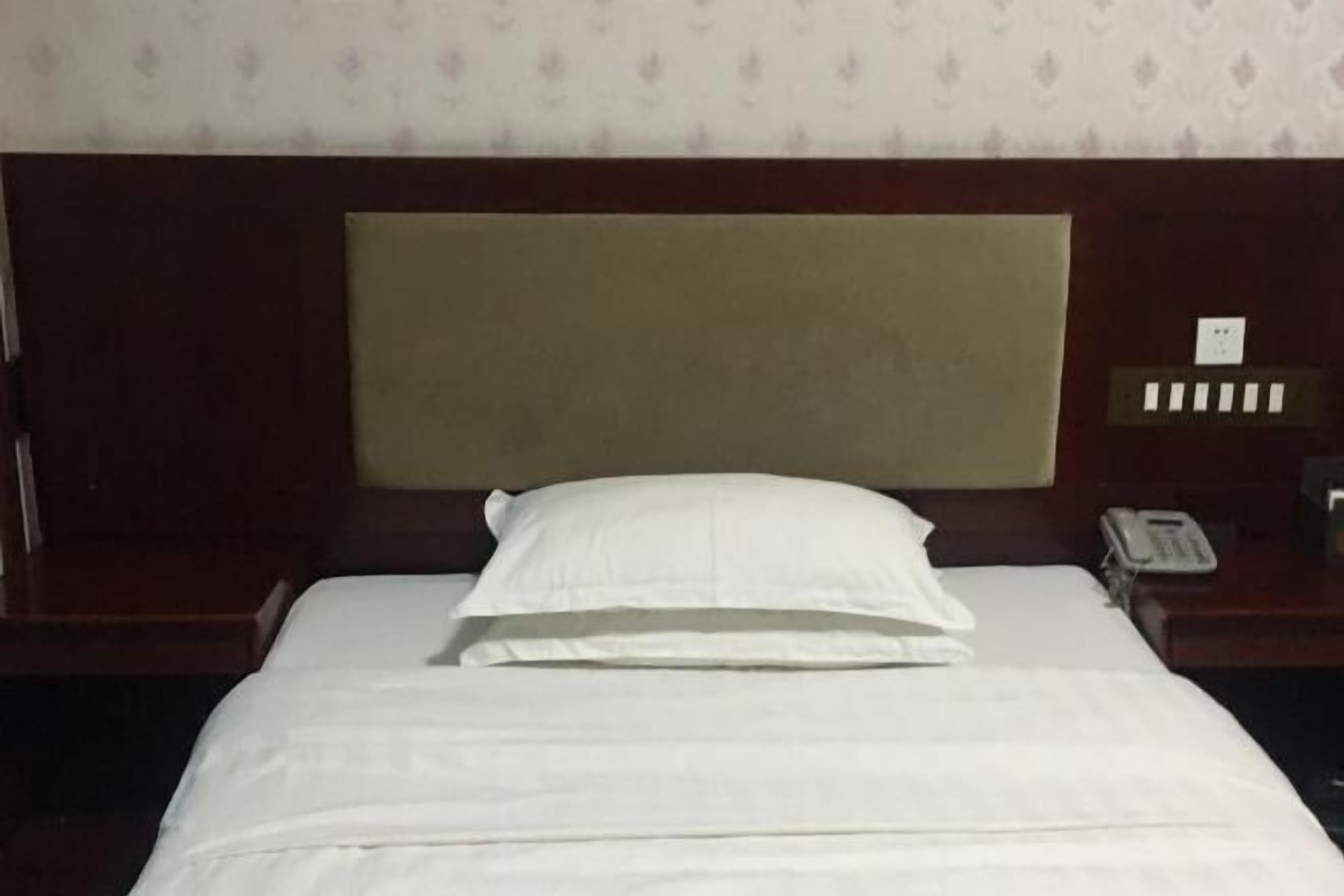 Une chambre d’hôtel comprenant un lit, une tête de lit, une table de chevet et un téléphone.