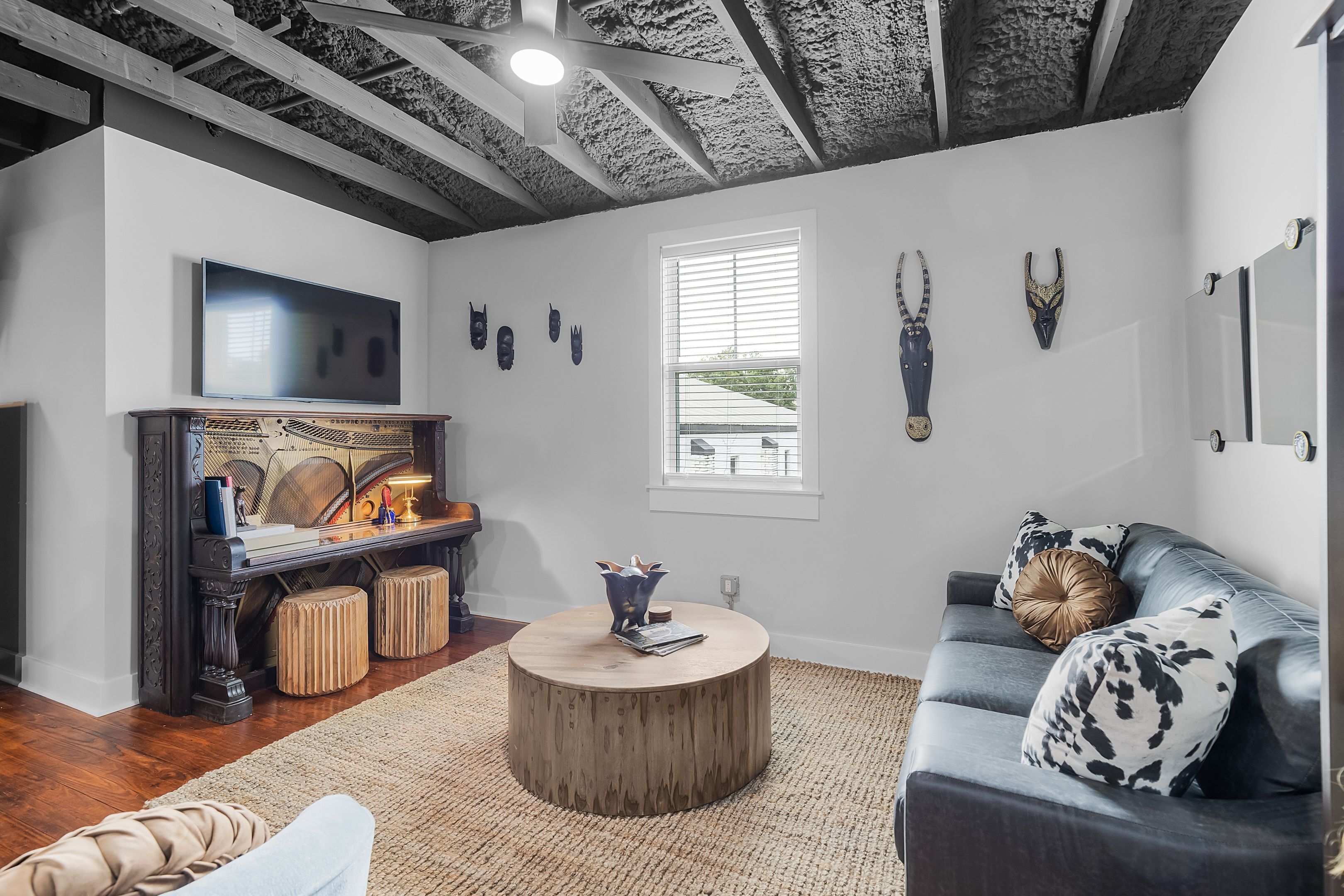 A living room with a round wooden coffee table, a dark blue sofa with patterned cushions, a flat-screen TV mounted on the wall, and a fireplace with a decorative mantel.
