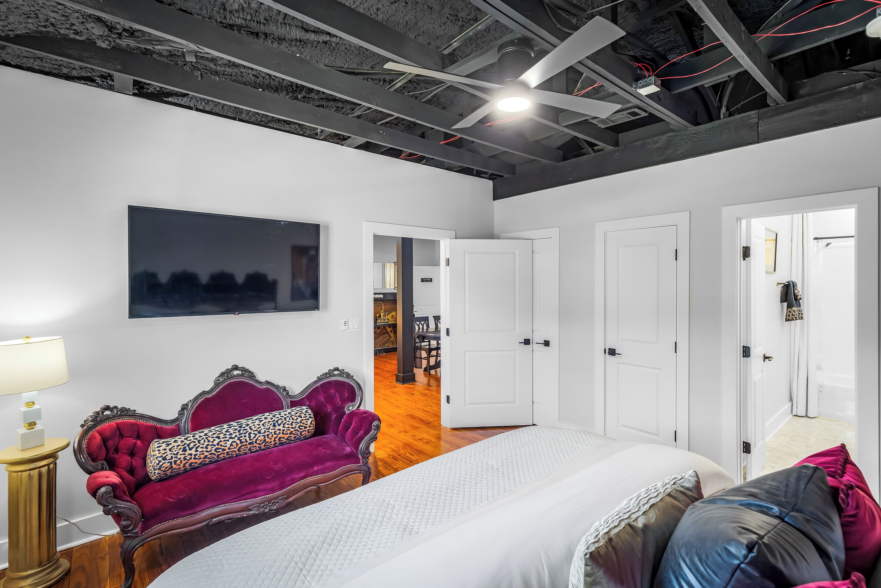 Un dormitorio con una cama grande, un sofá de terciopelo rojo y un cuadro de un paisaje urbano en la pared.
