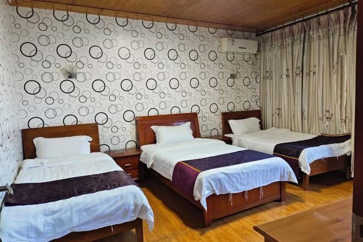 Una habitación de hotel con tres camas de madera, un papel tapiz estampado y piso de madera.