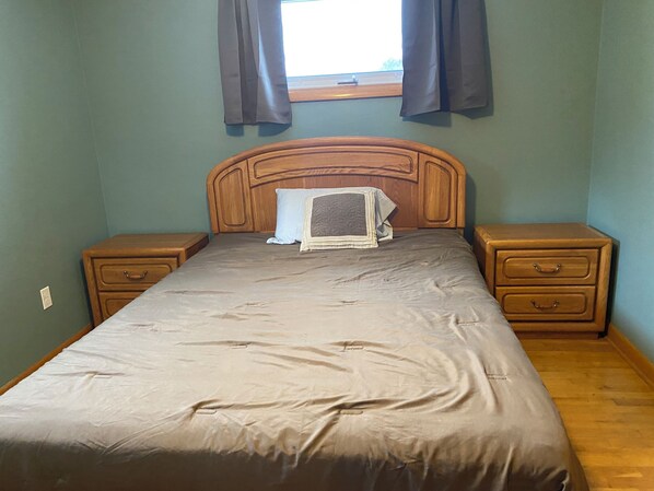 A bedroom with a wooden headboard, a single bed, two nightstands, and a window with curtains. - 3-bedroom house with spacious private yard and fire pit in Saint Marys (Saint Marys)