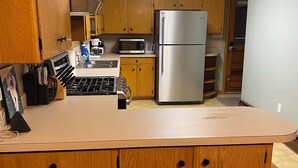 Una cocina con armarios de madera, un refrigerador de acero inoxidable, un microondas y una estufa a gas.