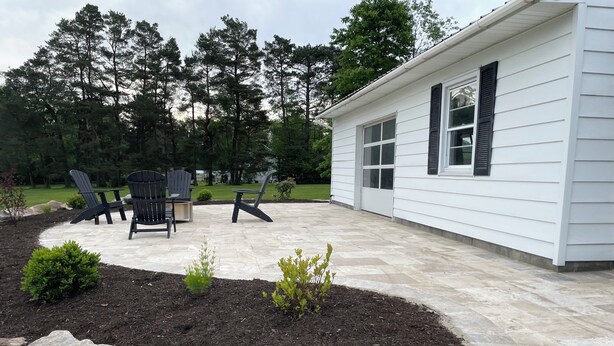 Un patio con suelo de piedra, mobiliario exterior y un pequeño jardín.