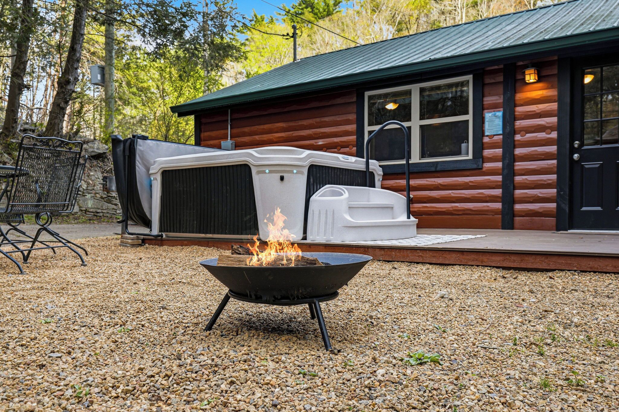 Une cabane en bois, avec un foyer au premier plan et un jacuzzi extérieur abrité à l’arrière-plan.