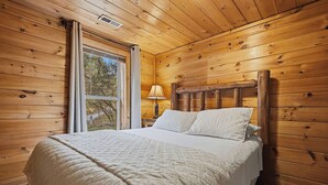 Una stanza con pannelli di legno, un letto, una finestra e una lampada.