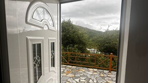 Una puerta blanca con un panel de vidrio, que da a un patio con suelo de piedra y barandilla de metal.