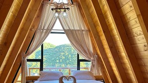 Un dormitorio acogedor en el ático, con techo inclinado de madera, una cama con sábanas blancas y una disposición de toallas en forma de corazón.