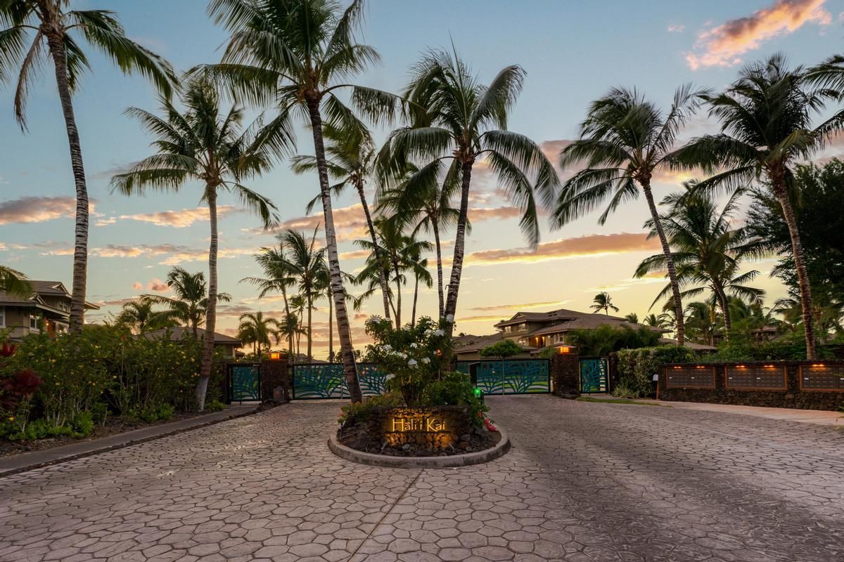 A paved entrance area with palm trees and a sign that reads 'Halimai Kai.'
