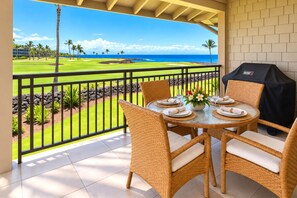 A balcony with a view of a golf course and the ocean.