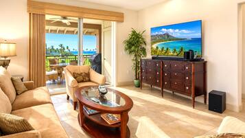 Living area at Halii Kai HLI-12A — flat-screen TV, ceiling fan, and sliding doors that open straight to the lanai