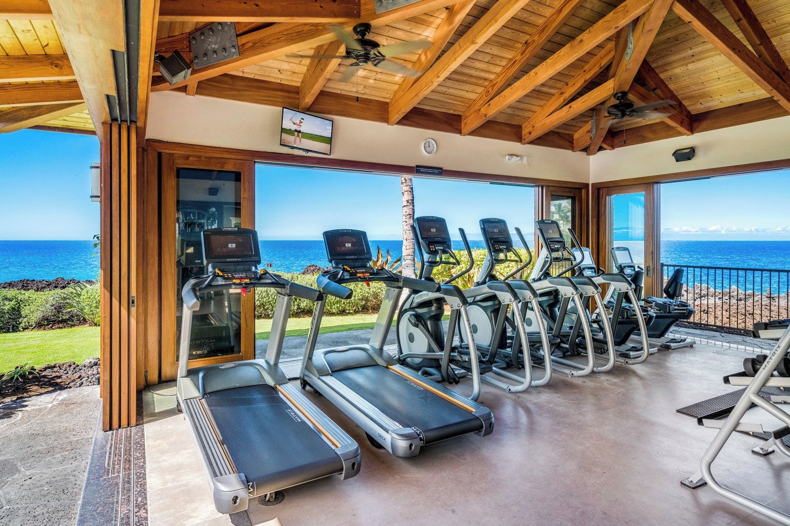 Ein Fitnessraum mit Laufbändern und Trainingsgeräten, der einen schönen Meerblick bietet.