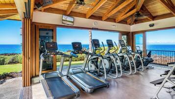 Ein Fitnessraum mit Laufbändern und Trainingsgeräten, der einen schönen Meerblick bietet.