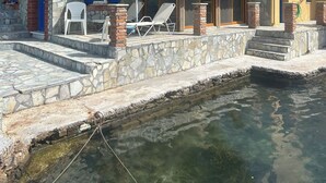 Ein Steinhaus mit Pool, Sitzgelegenheiten im Freien und freiem Blick auf das Wasser.