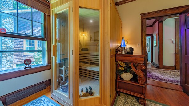 Une pièce avec un meuble en bois, une porte en verre donnant sur un placard, un tapis bleu à motifs et un plancher en bois.