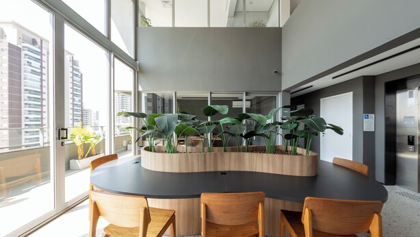 A modern conference room with a round table, four wooden chairs, and a central plant arrangement. - Charlie Wonder Brooklin (São Paulo)