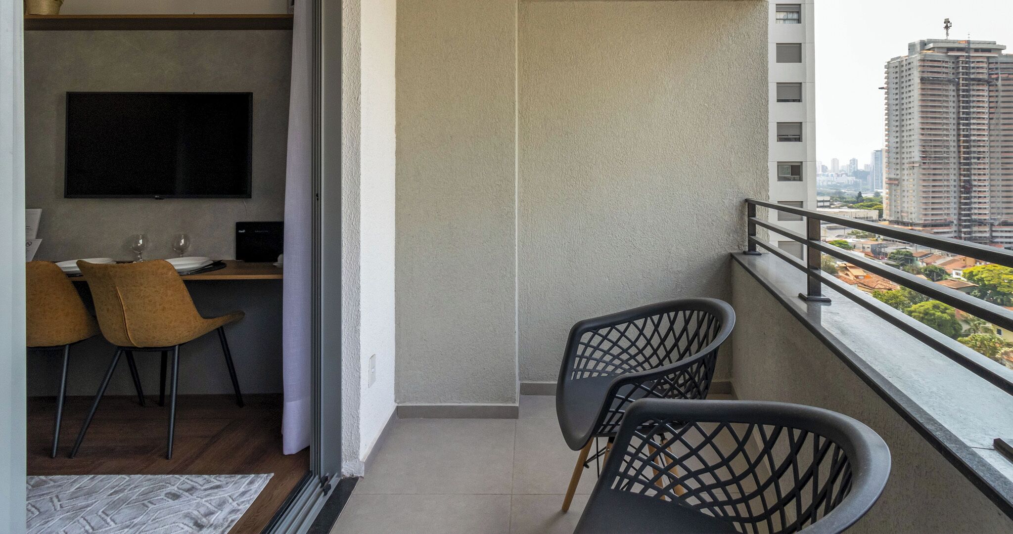 Un balcon avec deux chaises, une petite table et un téléviseur.