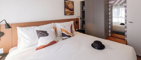 Una habitación de hotel con una cama bien hecha, un armario y un escritorio con lámpara.