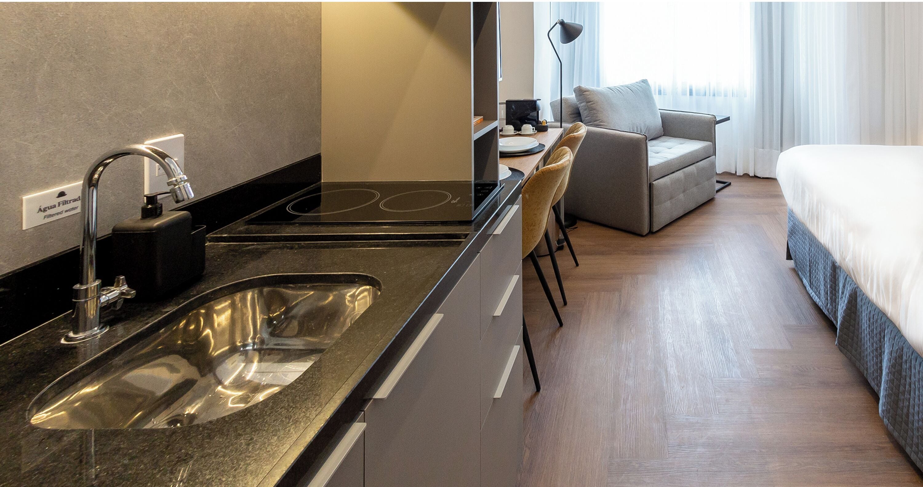 Een moderne hotelkamer met een kitchenette, een bank en een bed.