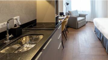 Een moderne hotelkamer met een kitchenette, een bank en een bed.