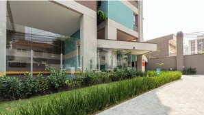 A modern building with large windows, a glass facade, and a landscaped area with green plants. - Charlie Wonder Brooklin (São Paulo)